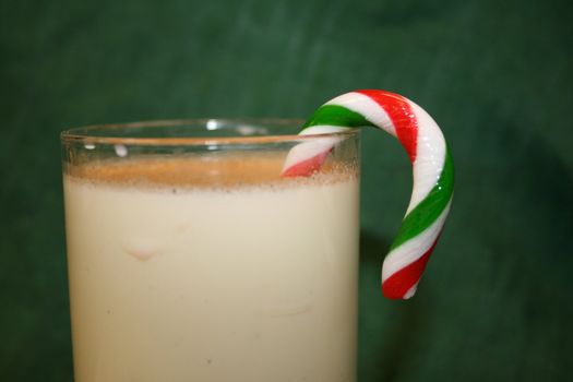 Clear mugs of egg nog with candy cane garnish