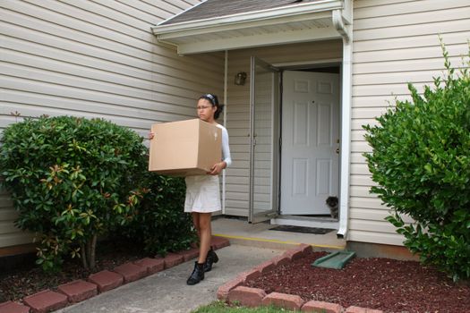 Attractive teen carrying box out of house