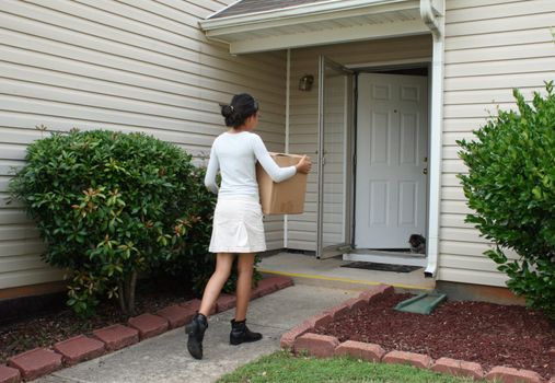 Attractive teen carrying box into house