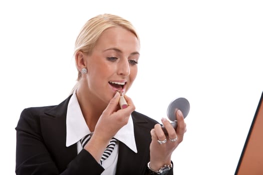 Beautiful blond woman in business suit applying her makeup