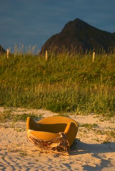 Old abandoned yellow armchair with seaview on a sandy beach close to Ramberg, Lofoten, Norway lit be the yellow midnight sun (Selective Focus, Focus on the armchair)