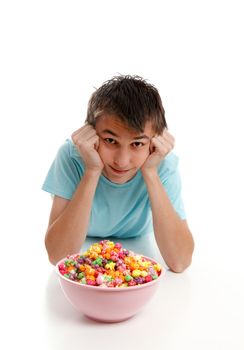 A boy lying down with head in hands.  A large bowl of snack food popcorn with him.  He is looking up and smiling.  White background.