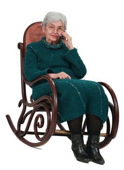 Image of an old woman sitting  in a rocker and using a mobile phone.