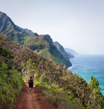 Kalalau trail path on Na Pali coast with three female hikers