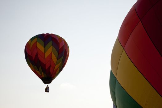 Hot air balloon rising and passing by a second balloon still on the ground