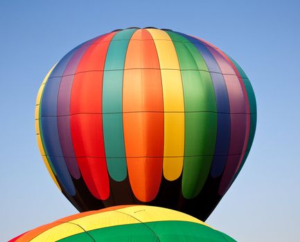 Colorful hot air balloon rising into the air above the canopy of another