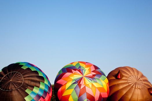 Three colorful hot air ballons being set up for a flight