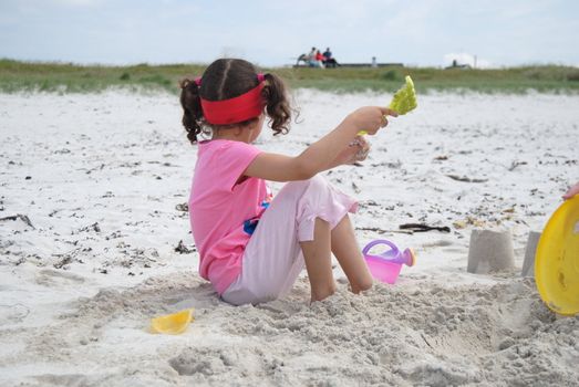 girl on beach with sand toys