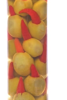 Isolated macro image of pickled pepper olives in a bottle.