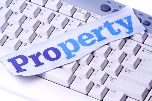 Image of a newspaper cutting with the words "Property" placed on a computer keyboard.