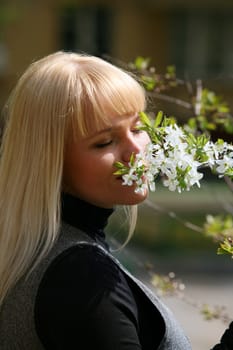 The beautiful Russian woman with a blossoming branch of a cherry