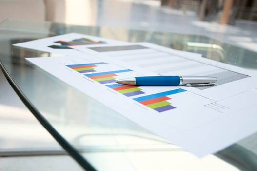 Business documents lay on a glass table at office