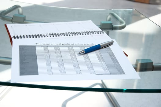 Tables, calendar, pen on a glass table at office