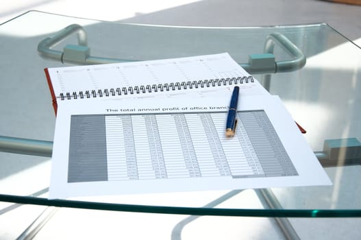 Tables, calendar, pen on a glass table at office