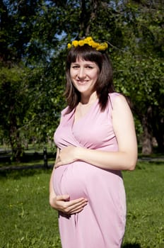 Portrait of the young beautiful girl in park, the girl embraces the stomach