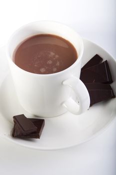 Hot chocolate in a white cup with peices of dark deluxe chocolate on the side