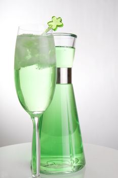 Bright green drink in a tall champagne glass and a can in the background