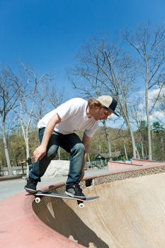 Action of a young skateboarder man skating down the side of the wall of the bowl at a skate park.