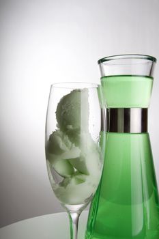 Bright green ice cream in a tall champagne glass and a can in the background