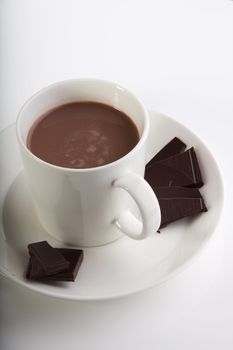 Hot chocolate in a white cup with peices of dark deluxe chocolate on the side