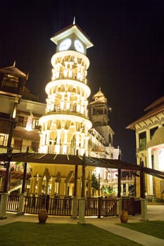 Night image of a clock tower in traditional Malaysian design in Malaysia.