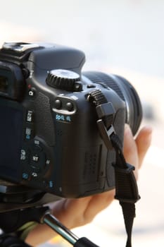 Woman photographer holding a photo camera outdoors.