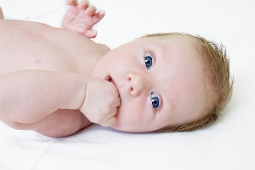 Adorable blue eyed boy lying on light background