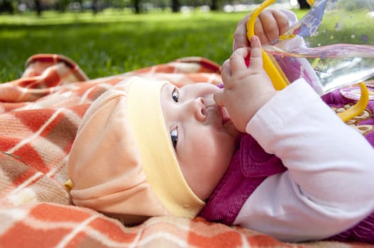 The portrait of the kid, lays on on a coverlet and drink water