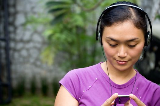 asian young woman with headphone listening music from mp3 player