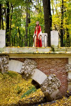 lady in medieval red dress in the autumn forest
