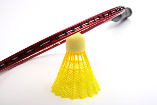 Yellow shuttlecock for badminton and a racket.