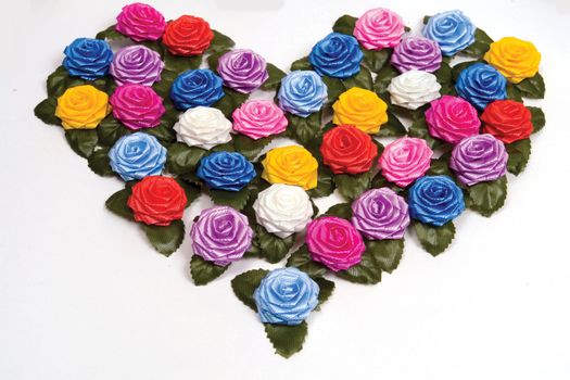 many-coloured plastics roses on a white background in shape heart