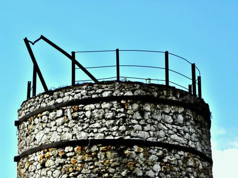 Part of tower of stones with barrier. Blue sky in the background.