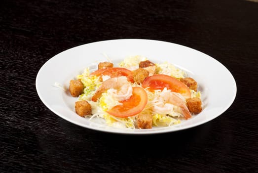 Salad of tiger shrimps, lettuce, chinese cabbage, tomato, garlic rusk, parmesan cheese and sauce