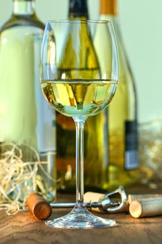 Glass of white wine with bottles on oak table