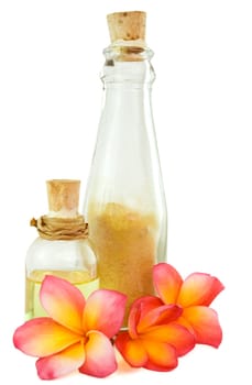 bottles of body oil and scrub powder as spa items with tropical flowers isolated on white