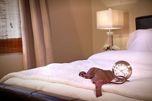 Lace brassiere laying across bed with clock