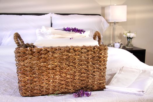 Linen basket with white sheets on bed
