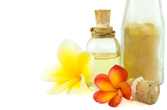 bottles of body oil and scrub powder as spa items with tropical flowers isolated on white