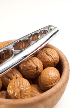 Bowl of walnuts and a steel nutcracker isolated on white