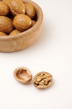 Open cracked walnut isolated on white with a wooden bowl in the background