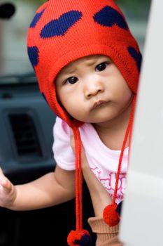 cute baby girl looking curiously (questioning) onto something from inside of a car