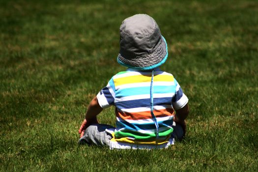 Toddler enjoying the sun while sitting in the grass