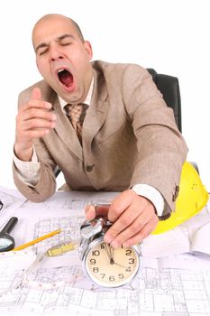 A businessman sleepy with architectural plans at desk