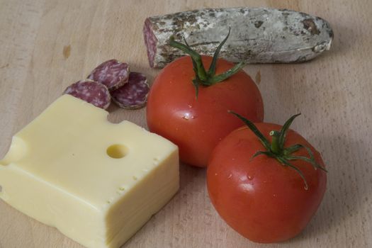 Italian sausage, tomatoes and cheese on a wood chopping board