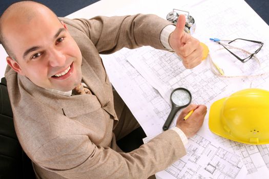 A businessman happiness with architectural plans at desk