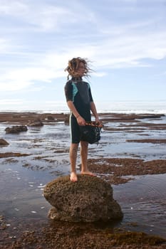 A young male stands on a rock on a stretch of beach on the East Coast of Southern Hawkes Bay. Between Porangahau and Whangaehu Beaches.