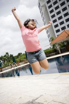 conceptual portrait of asian little girl jumping by the pool, excited on having a great vacation 