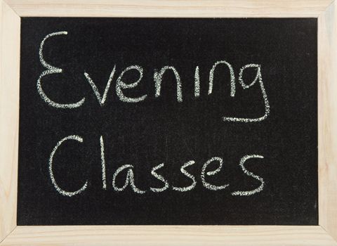 A black board with a wooden frame and the word 'EVENING CLASSES' written in chalk.
