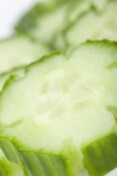 Closeup of cucumber slice with shallow depth of field and slices in the distance